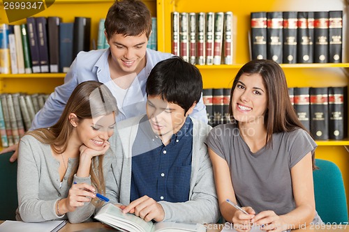 Image of Female Student With Friends Reading Book In Library