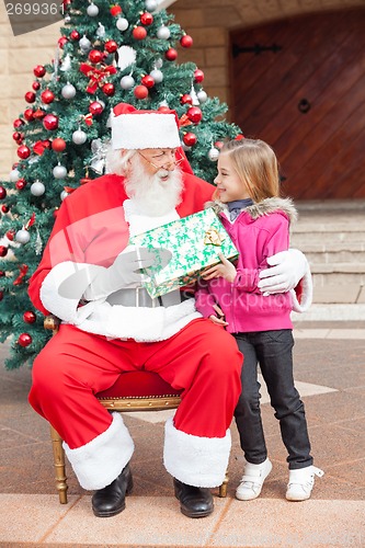 Image of Santa Claus Giving Gift To Girl