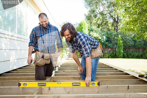 Image of Construction Workers Looking At Spirit Level On Plank