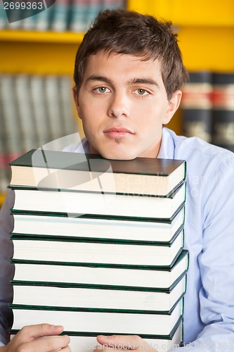 Image of Student Resting Chin On Stacked Books In Library