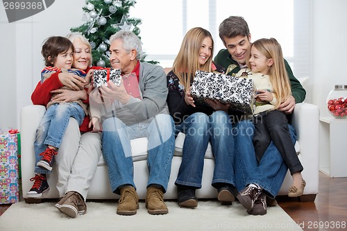 Image of Family With Christmas Presents Sitting In House