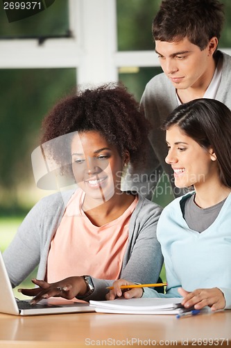 Image of Friends Using Laptop At Desk In Classroom