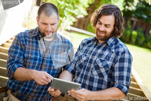 Image of Construction Workers Discussing Project On Digital Tablet