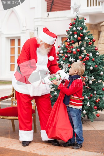 Image of Santa Claus Giving Present To Boy