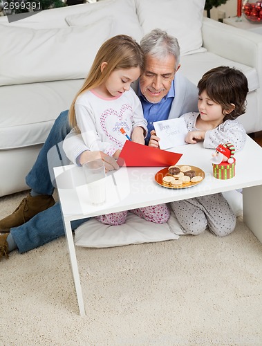 Image of Man Assisting Children In Making Christmas Greeting Card