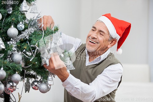 Image of Happy Senior Man Decorating Christmas Tree