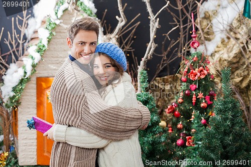 Image of Portrait Of Couple With Gift Box Embracing At Christmas Store