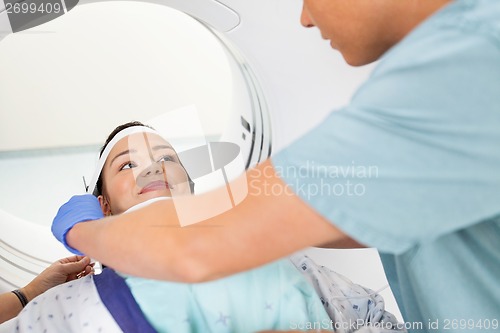 Image of Patient Looking At Nurse Adjusting Strap Before CT Scan