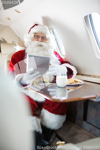 Image of Santa Holding Digital Tablet In Private Jet