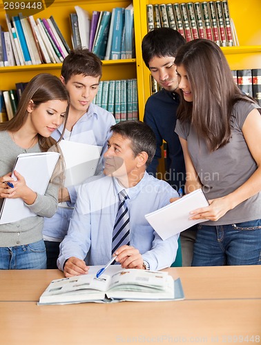Image of Teacher With Books Explaining Students In College Library