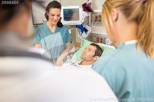 Image of Nurses And Doctor Examining Patient In Hospital