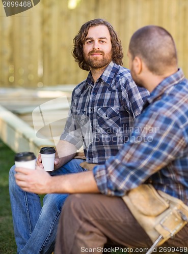 Image of Worker Holding Disposable Cup While Sitting With Coworker