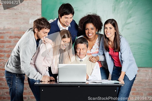 Image of Students Standing With Classmates While Teacher Teaching On Lapt