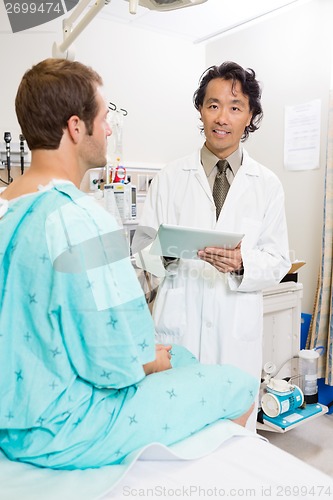 Image of Doctor Holding Digital Tablet With Patient Sitting On Bed