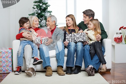 Image of Family With Christmas Presents Sitting On Sofa