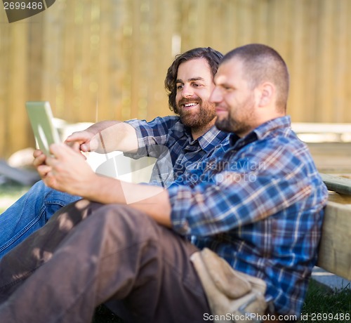 Image of Carpenter Holding Digital Tablet While Coworker Pointing At It