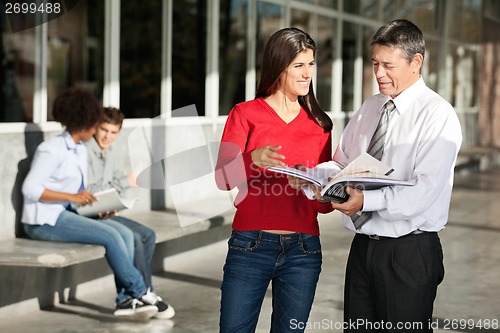 Image of Female Student And Teacher Discussing Over Book On Campus