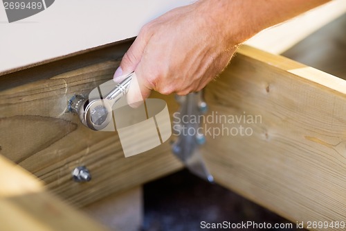 Image of Carpenter's Hand Tightening Bolt With Wrench