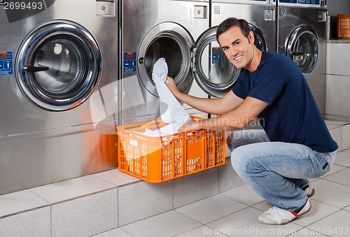Image of Young Man Putting Clothes In Washing Machine