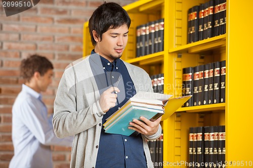 Image of Male Student Reading Book In College Library