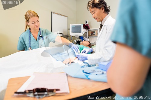 Image of Nurse Assisting Doctor In Stitching Wound On Patient's Hand