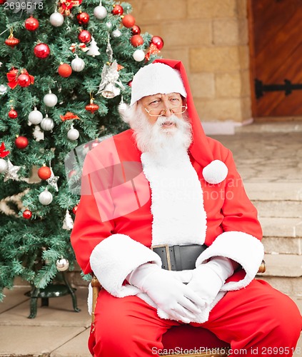 Image of Man Dressed As Santa Claus Sitting In Front Of House