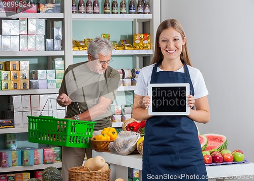 Image of Saleswoman Showing Digital Tablet While Senior Man Shopping