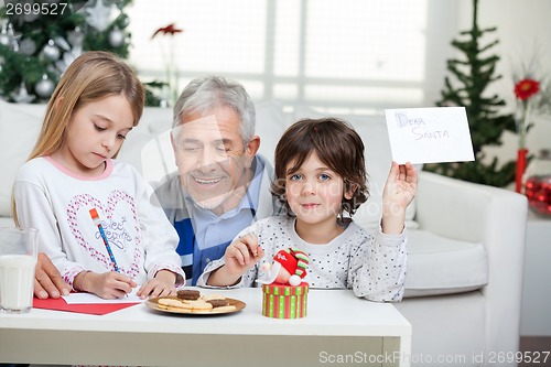 Image of Boy Showing Letter While Grandfather Assisting Girl