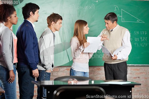 Image of Teacher Gesturing Thumbsdown While Looking At Student In Classro