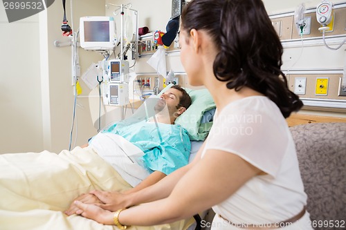 Image of Woman Holding Man's Hand Lying On Bed