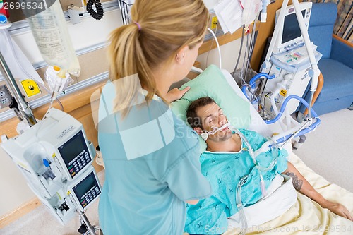 Image of Nurse Adjusting Young Patient's Pillow In Hospital