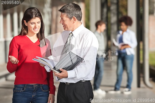 Image of Teacher And Student Discussing Over Book On Campus