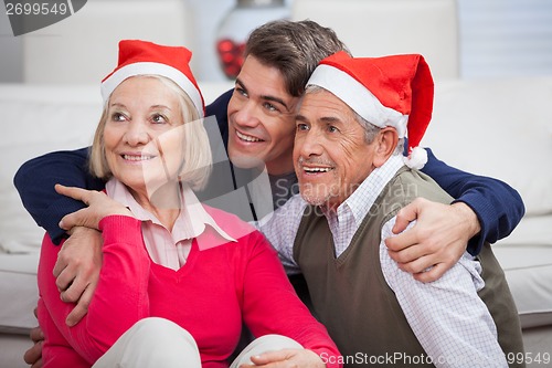 Image of Loving Son With Parents Wearing Santa Hats