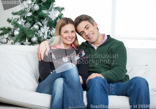 Image of Loving Couple Sitting On Sofa During Christmas