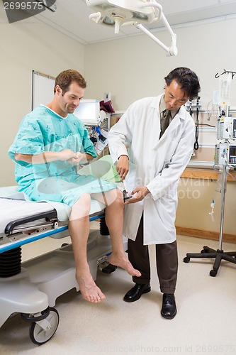 Image of Doctor Examining Patient's Knee With Hammer In Hospital
