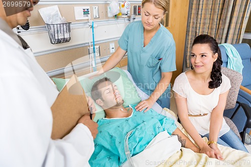 Image of Woman Looking At Doctor While Holding Man's Hand