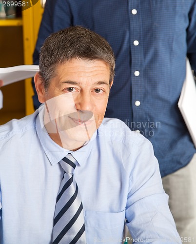 Image of Confident Teacher Smiling With Student Standing In Background At