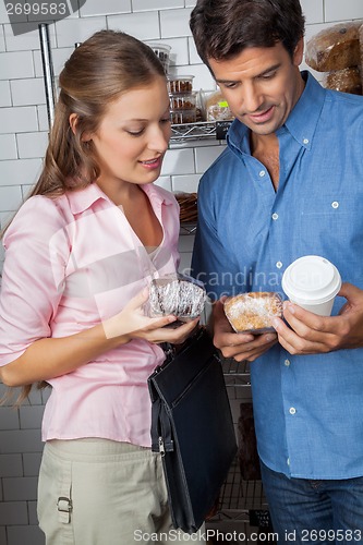 Image of Couple Holding Cakes And Coffee Cup At Grocery Store