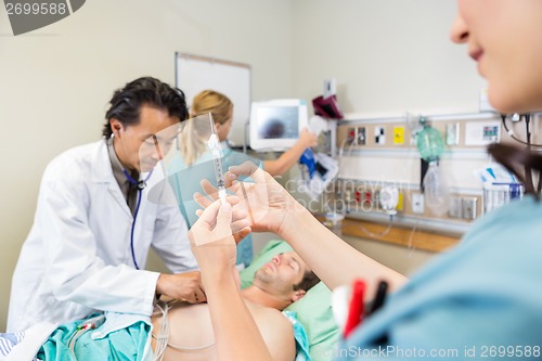 Image of Nurse Preparing Injection While Doctor And Colleague Examining P