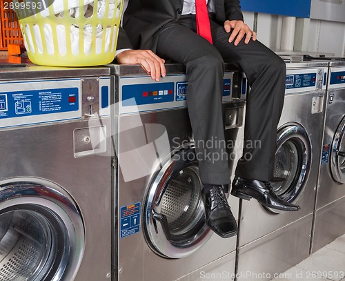 Image of Businessman Sitting On Washing Machine