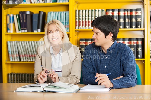 Image of Confident Teacher With Student Looking At Her In Library