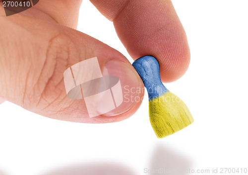 Image of Hand holding wooden pawn, flag painting, selective focus