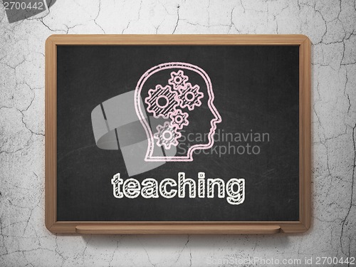 Image of Education concept: Head With Gears and Teaching on chalkboard background