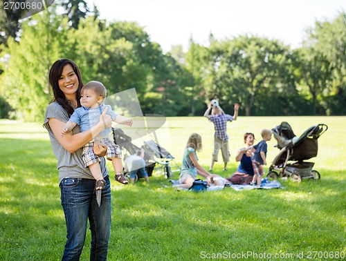 Image of Happy Mother Carrying Baby Boy At Park