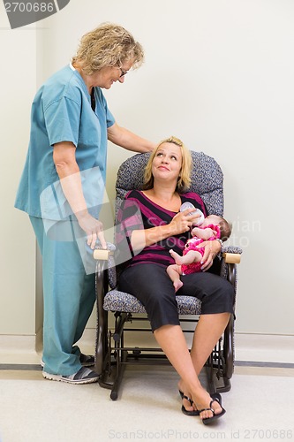 Image of Mother Feeding Milk To Newborn Babygirl While Looking At Nurse