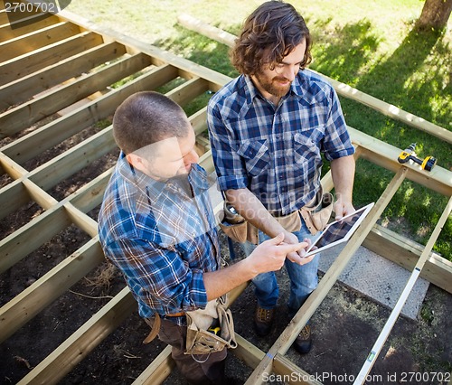 Image of Carpenters Discussing Project On Digital Tablet