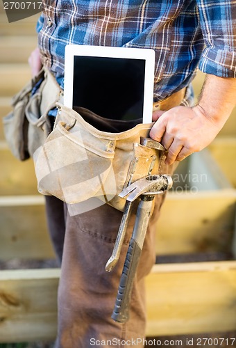 Image of Midsection Of Carpenter With Tablet Computer And Hammer In Toolb