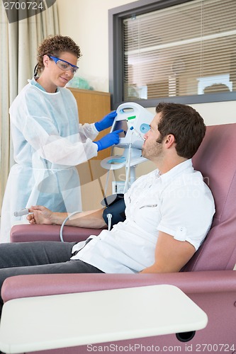 Image of Nurse Looking At Patient While Operating Heartbeat Monitor In Ho