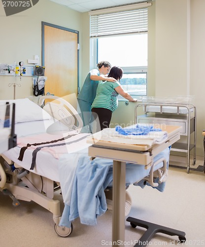 Image of Nurse Comforting Pregnant Woman At Window In Hospital Room