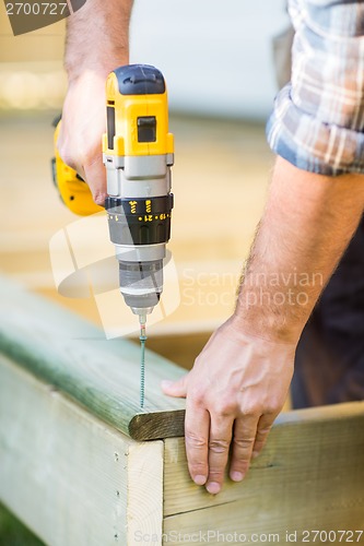 Image of Carpenter's Hands Using Drill On Wood